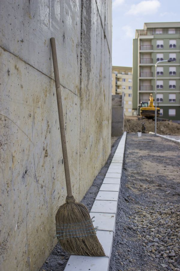 Besen lehnt an einer Betonwand auf einer Baustelle